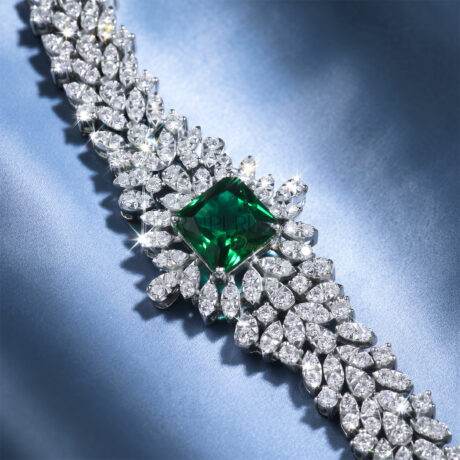 Vibrant Square cut green sapphire and sparkling moissanite statement link bracelet in 925 sterling silver displayed diagonally on a soft blue silk background.