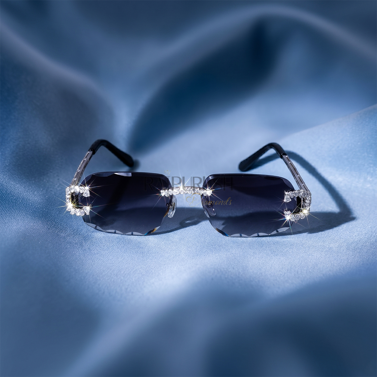 Luxury rimless sunglasses with dark tinted lenses and iced out moissanite stone frames resting on a smooth blue silk background.