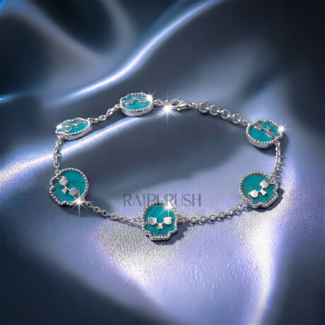 Unisex 925 sterling silver hip hop station bracelet featuring five skull-shaped turquoise stones framed with milgrain borders.Full length view of an edgy streetwear turquoise skull link chain bracelet laid out on a shimmering blue satin surface.
