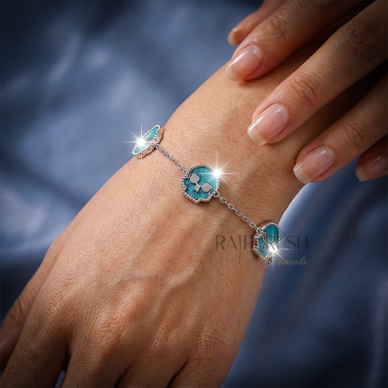Unisex 925 sterling silver hip hop station bracelet featuring five skull-shaped turquoise stones framed with milgrain borders.Full length view of an edgy streetwear turquoise skull link chain bracelet laid out on a shimmering blue satin surface.