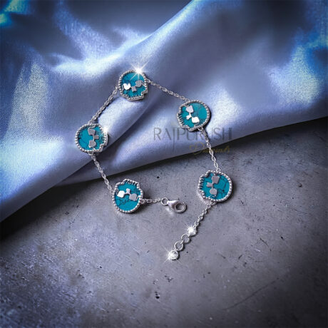 Unisex 925 sterling silver hip hop station bracelet featuring five skull-shaped turquoise stones framed with milgrain borders.Full length view of an edgy streetwear turquoise skull link chain bracelet laid out on a shimmering blue satin surface.