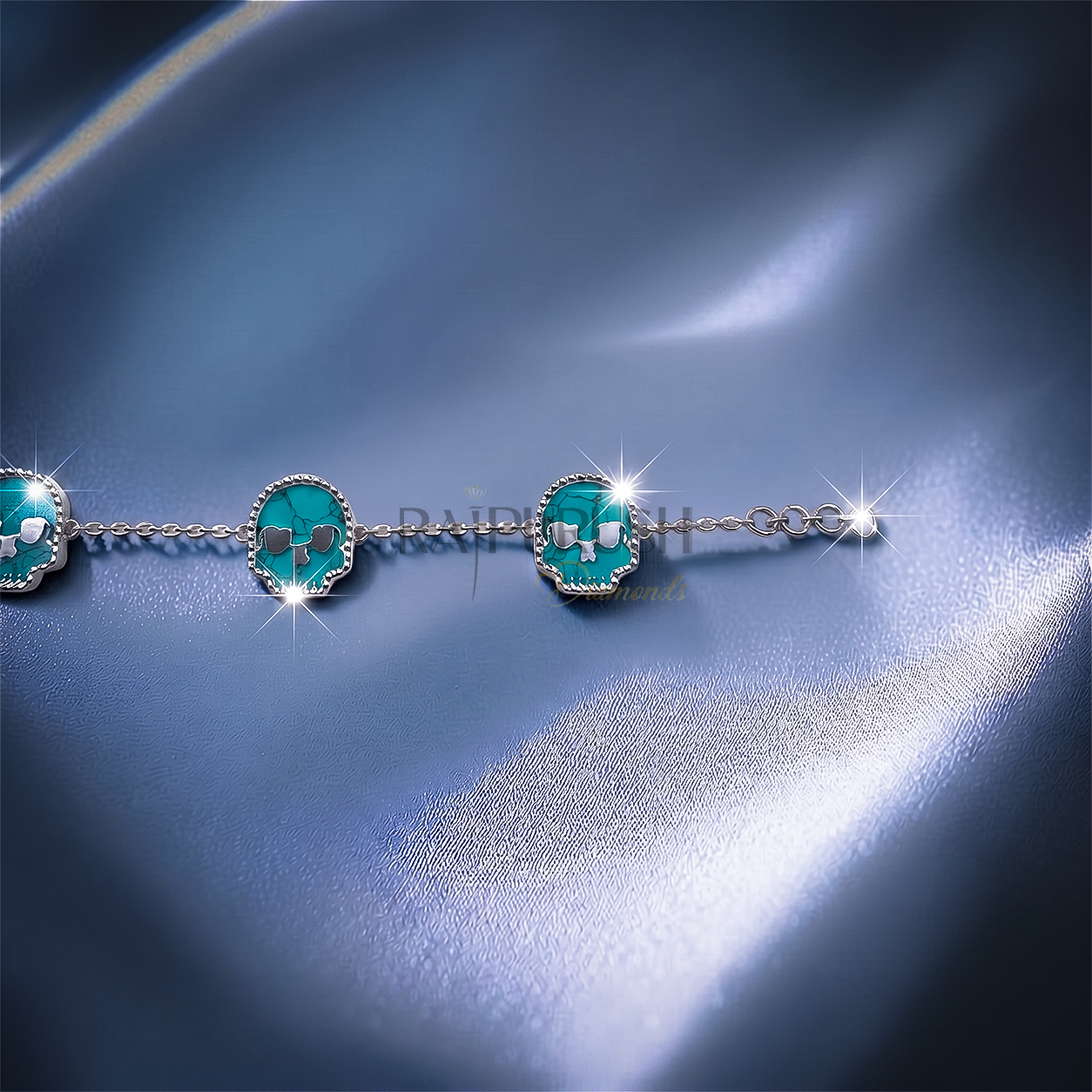 Unisex 925 sterling silver hip hop station bracelet featuring five skull-shaped turquoise stones framed with milgrain borders.Full length view of an edgy streetwear turquoise skull link chain bracelet laid out on a shimmering blue satin surface.