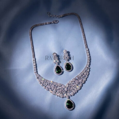 Stunning round brilliant moissanite tennis necklace featuring green sapphire pear cut diamond alternative teardrop clusters on a luxurious blue silk background.