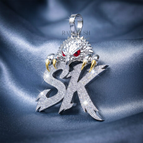 A custom iced-out "SK" initial pendant featuring an eagle design with red enamel eyes and gold-plated claws