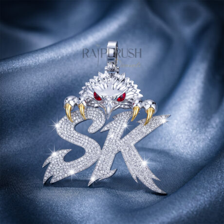 A custom iced-out "SK" initial pendant featuring an eagle design with red enamel eyes and gold-plated claws