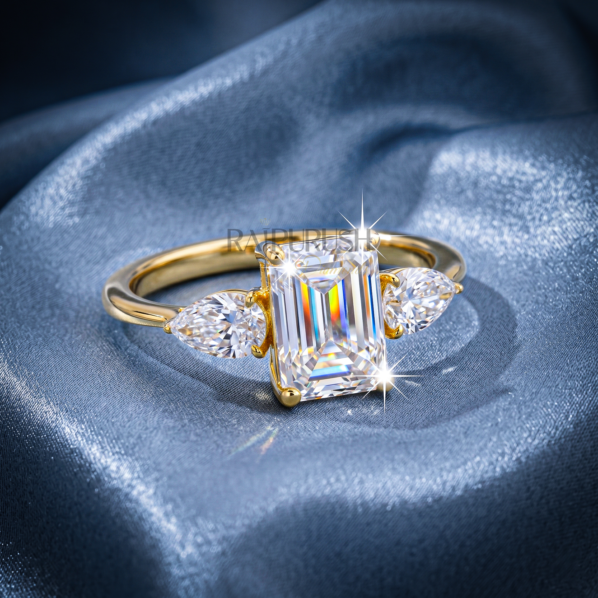 Elegant emerald-cut moissanite engagement ring with pear-shaped side stones, finished in 14k yellow/rose gold plating.
