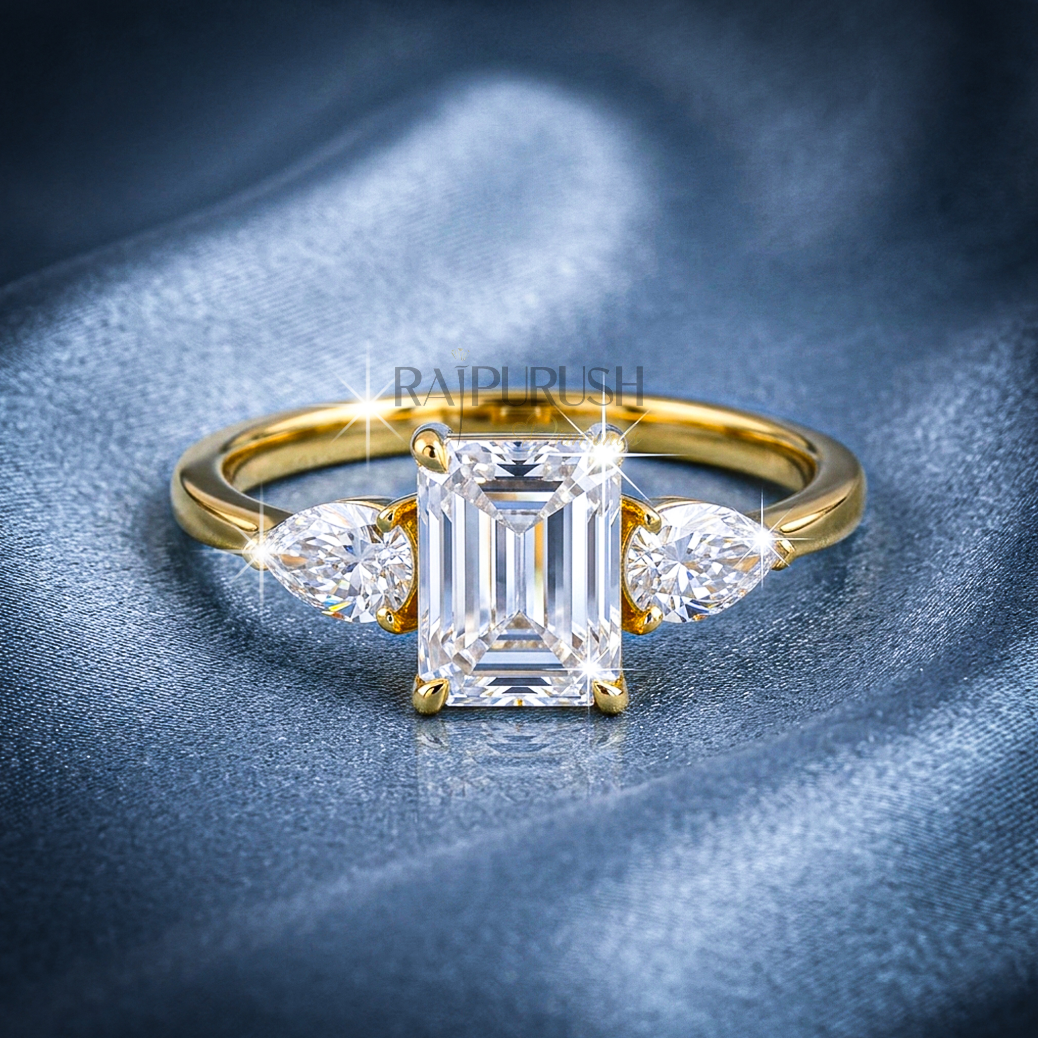 Elegant emerald-cut moissanite engagement ring with pear-shaped side stones, finished in 14k yellow/rose gold plating.