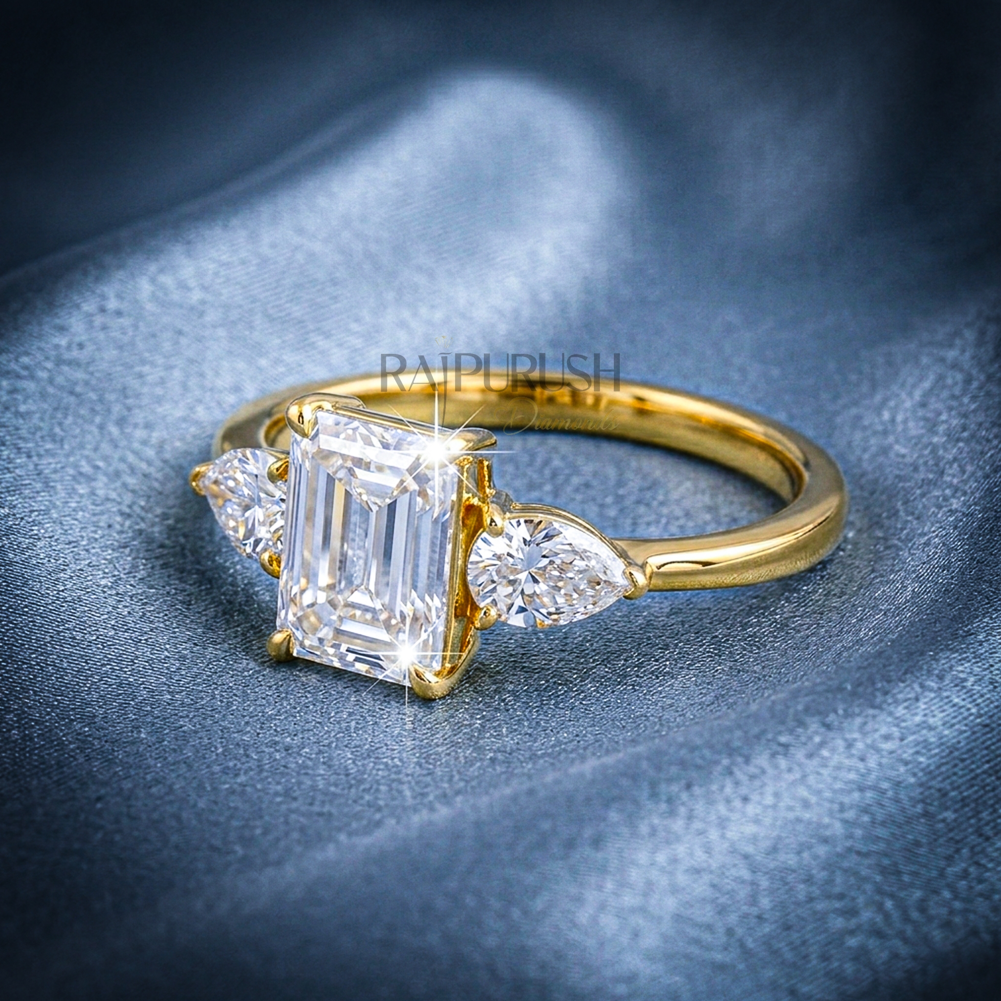 Elegant emerald-cut moissanite engagement ring with pear-shaped side stones, finished in 14k yellow/rose gold plating.