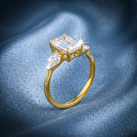 Elegant emerald-cut moissanite engagement ring with pear-shaped side stones, finished in 14k yellow/rose gold plating.