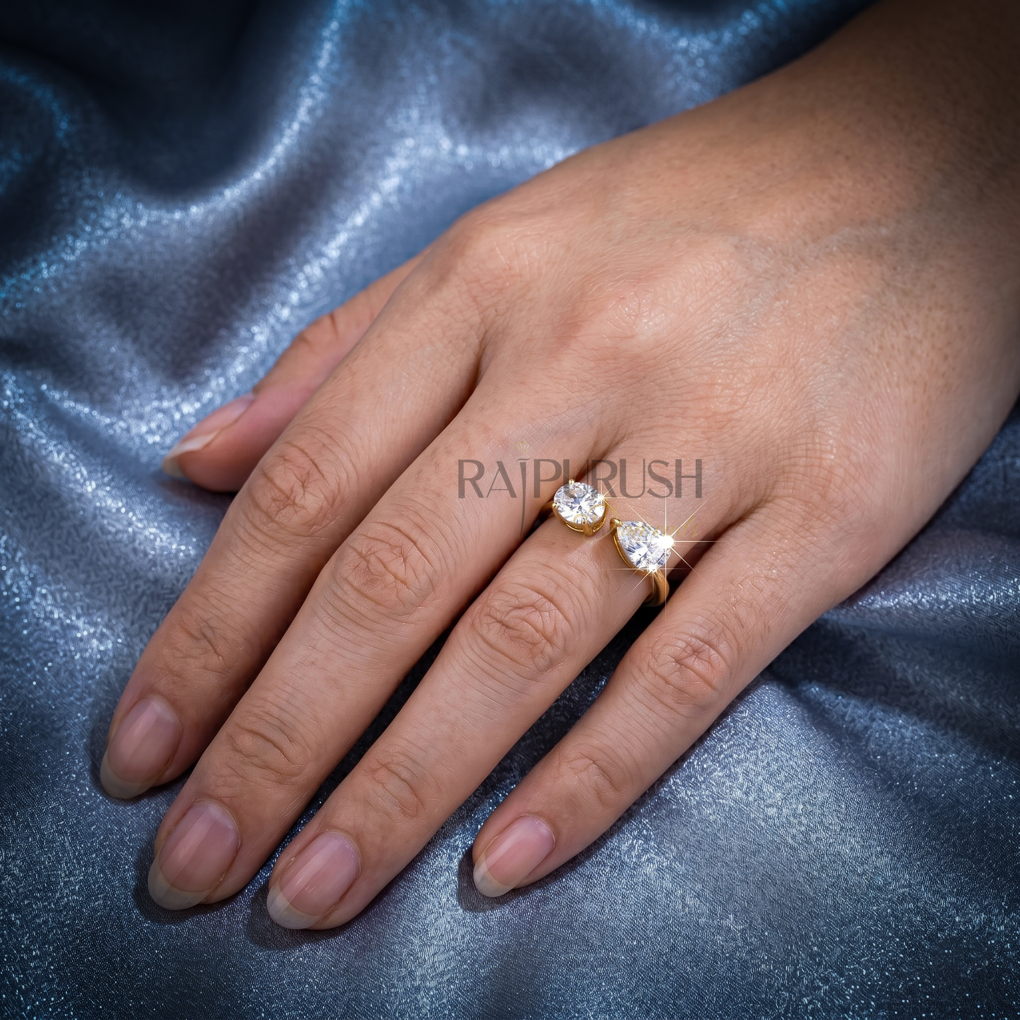 A modern "Toi et Moi" style engagement ring featuring pear and oval cut moissanite stones, finished in 14k yellow/rose gold plating.