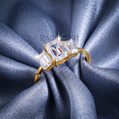 Classic three-stone engagement ring featuring a central emerald-cut moissanite flanked by two emerald side stones, finished in 14k yellow/rose gold plating.