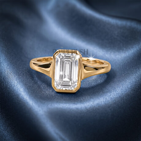 A stunning 1ct emerald cut moissanite engagement ring featuring a secure full bezel setting on a polished 14k gold band