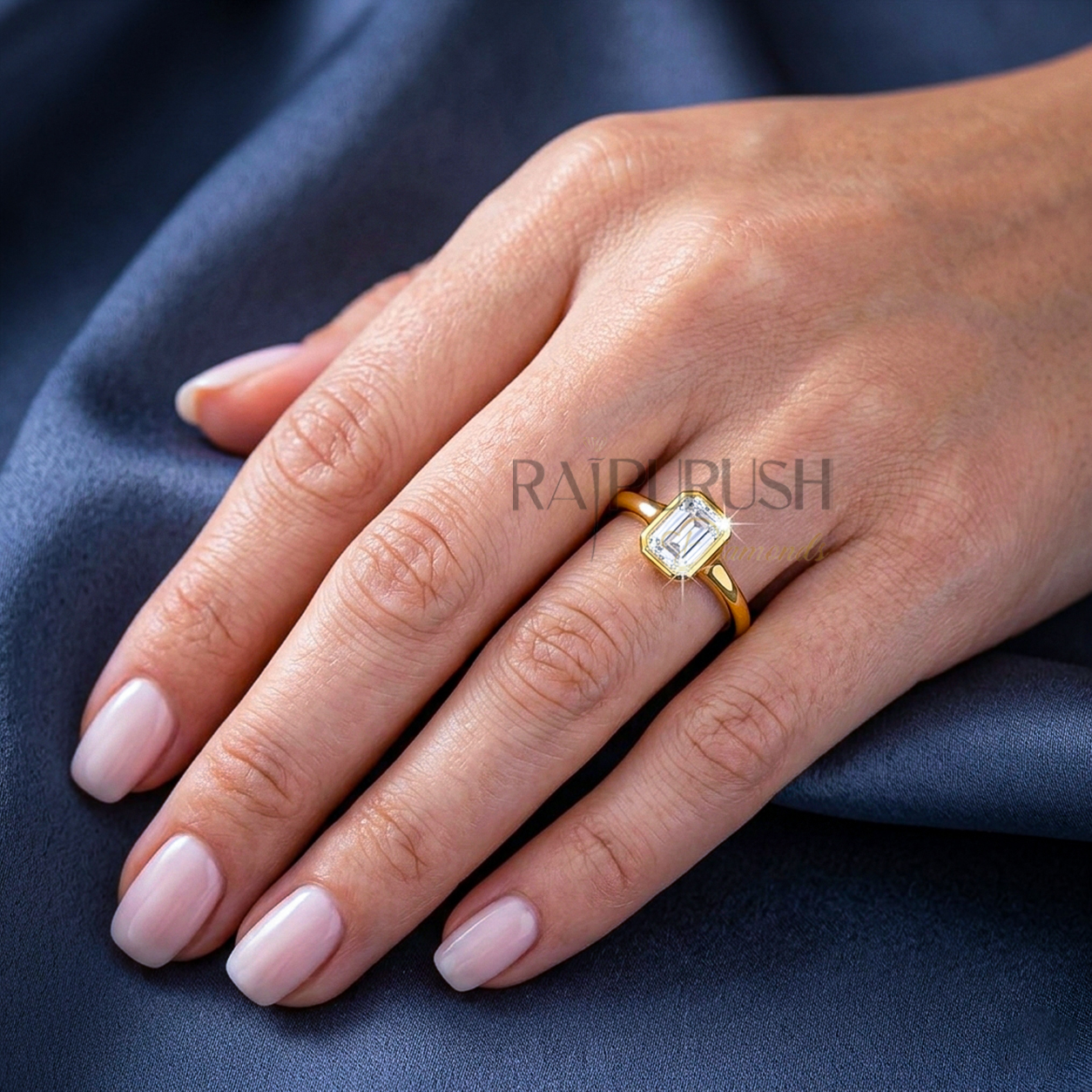 A stunning 1ct emerald cut moissanite engagement ring featuring a secure full bezel setting on a polished 14k gold band