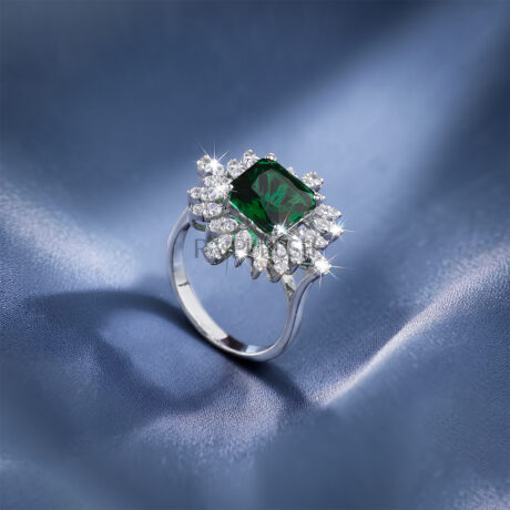 Vibrant Square cut green sapphire center stone inside a sparkling moissanite snowflake cluster halo ring crafted in 925 sterling silver on blue silk.