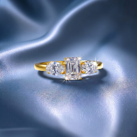 Vintage-inspired emerald cut moissanite engagement ring featuring a three-stone layout in 925 sterling silver on blue silk.